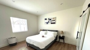 A bedroom with a bed, a nightstand, a lamp, a window, and a wall-mounted artwork. - Charming 2-bedroom apartment with WiFi, AC in beautiful Burbank (Burbank)
