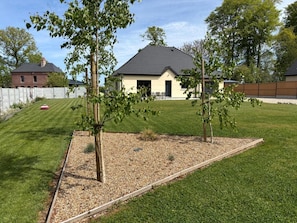 Ein Wohngebiet mit einem gepflegten Rasen, einem kleinen Baum und einem Haus mit dunklem Dach.