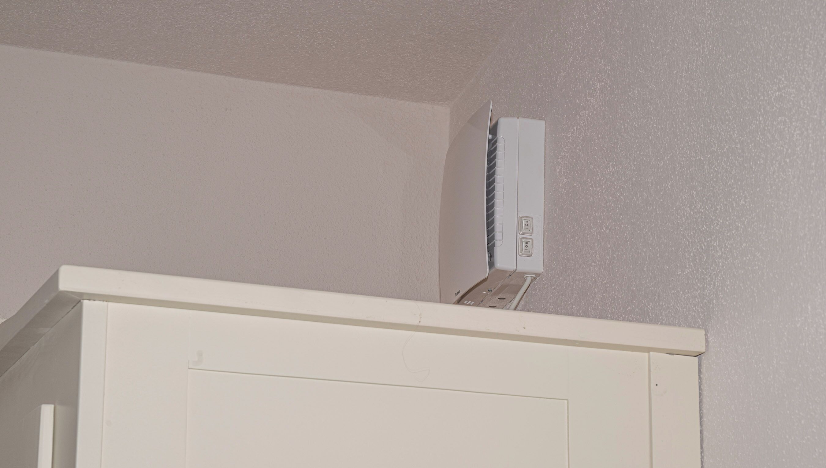Un appareil de climatisation blanc est fixé au mur dans une pièce dont la porte est également blanche.