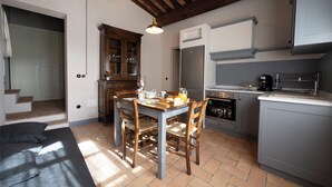 A kitchen with a dining table, chairs, a refrigerator, and a sink.