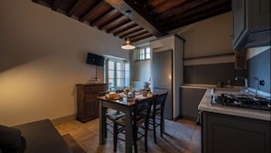 A kitchen with wooden beams, a dining table with chairs, a stove, and a refrigerator.