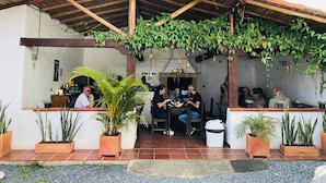 An outdoor seating area with a wooden pergola, potted plants, and a tiled floor. - Hotel Ruta 40 Villa de Leyva (Villa de Leyva)