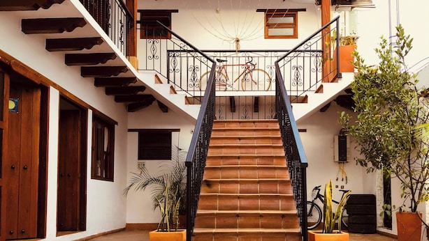 A staircase with a wooden finish, black railings, and potted plants at the base. - Hotel Ruta 40 Villa de Leyva (Villa de Leyva)
