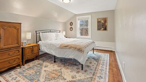 A bedroom with a bed, wooden nightstand, dresser, and a window with a view of trees. - Updated & Great Downtown Location, Built 1841 (Salem)