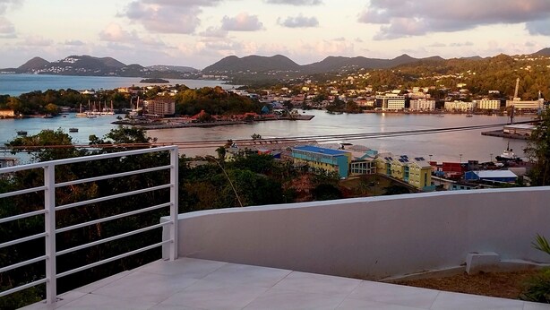 A coastal cityscape with a view of the sea, buildings, and mountains in the background. - Awesome Homes - Harbour View (Castries)