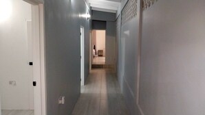 A hallway with grey walls, a white door on the left, and a light fixture on the right. - Awesome Homes - Harbour View (Castries)