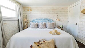 Un dormitorio con una cama grande, un cabecero de madera, una ventana con cortinas y una puerta.