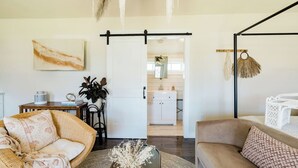 A spacious living area with a sofa, a coffee table, and a dining table. There is a sliding door leading to a kitchen and a bathroom.