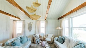 A cozy living room with two sofas, a wicker coffee table, and a hanging light fixture. - Hidden gem in Kure|2min walk to Beach|Hot Tub (Kure Beach)