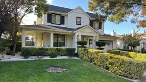 A two-story house with a well-maintained lawn, a covered porch, and a driveway. - Spacious cozy Oasis retreat with private pool  Backyard (Modesto)