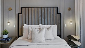Ein modernes Schlafzimmer mit einem großen Bett, einer außergewöhnlichen Chandelier und einem kleinen Nachttisch.