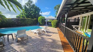 A poolside area with lounge chairs and a pergola. - T2 CREOLE apartment by the pool (Sainte-Luce)