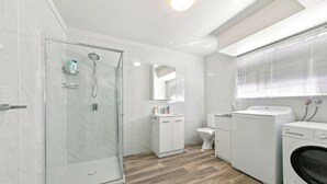 Ein modernes Badezimmer mit Duschkabine, Toilette, Waschbecken und Waschmaschine.