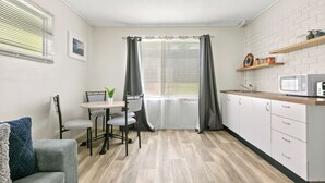Eine kompakte Küche mit Essbereich, weißen Schränken, einer Mikrowelle und einem kleinen Tisch mit Stühlen.