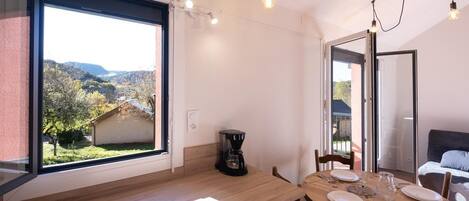 A modern kitchen with a large window, a coffee machine, and a dining area with a table set for two.