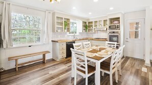 A modern kitchen with white cabinetry, a dining table with chairs, a bench, and a built-in oven. - Charming 5bd/4ba 15mi BNA 7mi Broadway 6mi Vandy (Nashville)