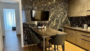 Una cocina moderna con salpicadero de mármol, televisor de pantalla plana y barra con botellas de vino.