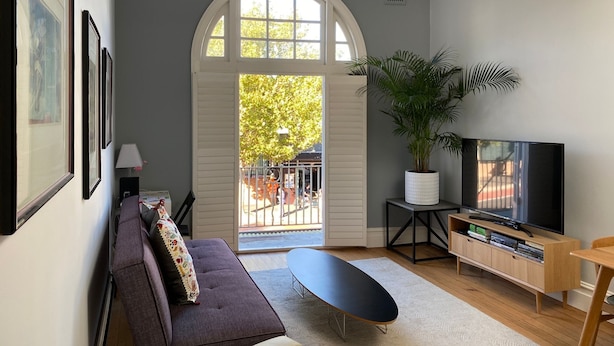 Un salon comprenant un canapé, une table basse, un téléviseur et une grande fenêtre donnant sur l’extérieur.
