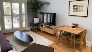 Un salon moderne avec un téléviseur, une table à manger et une grande fenêtre.