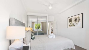 A hotel room with a bed, a bedside table with a lamp, a mirror, and a framed picture on the wall.