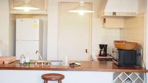 A kitchen with a wooden countertop, a refrigerator, a coffee maker, and a basket on the stove. - Apartment in Club Santiago (Manzanillo)