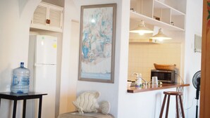A kitchen with a water dispenser, a fish sculpture, a framed painting, and a microwave. - Apartment in Club Santiago (Manzanillo)