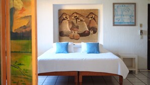 A bedroom with a large bed, two pillows, a small bedside table, and a painting on the wall. - Apartment in Club Santiago (Manzanillo)