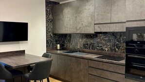 Una cocina moderna con salpicadero de mármol, muebles oscuros y horno empotrado.