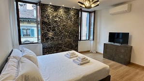 Una habitación de hotel moderna con una cama, un televisor y una pared de mármol.