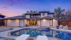 A modern house with a swimming pool, outdoor seating, and a well-lit garage. - Family & Dog-Friendly Luxury Tudor Home in Richardson, TX w/ Pool and Spa (Richardson)