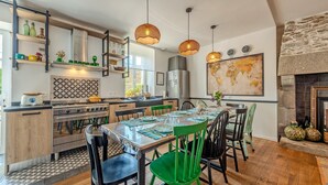 A modern kitchen with a dining area, wooden cabinets, a stove, and hanging pendant lights. - Holiday Home 'Maison 8 Pers Plein Centre Ville' with Private Terrace, Garden & Wi-Fi (Lesneven)