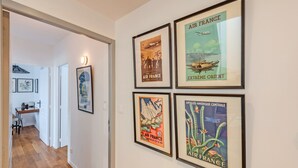 A hallway with framed vintage posters on the wall and a desk with chairs in the background. - Holiday Home 'Maison 8 Pers Plein Centre Ville' with Private Terrace, Garden & Wi-Fi (Lesneven)