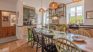 A modern kitchen with a dining area, featuring a large island, pendant lights, and a view of the outdoors. - Holiday Home 'Maison 8 Pers Plein Centre Ville' with Private Terrace, Garden & Wi-Fi (Lesneven)