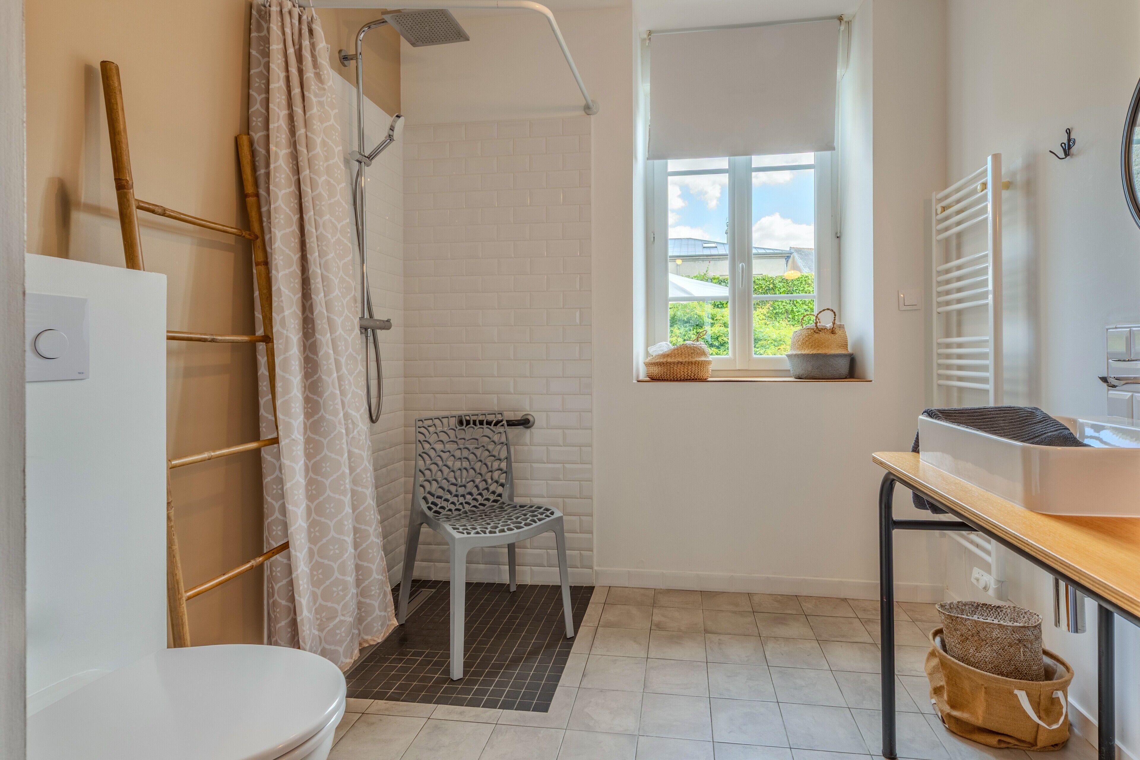 Een badkamer met douche, toilet en een raam met uitzicht.