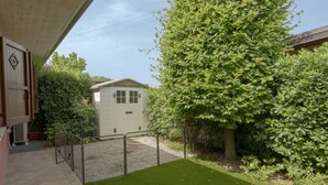 A fenced backyard with a small shed, a tree, and a well-maintained lawn.
