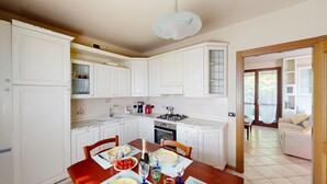 A kitchen with white cabinets, a dining table set with plates, glasses, and a bottle.