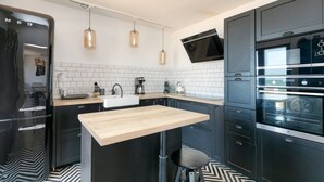 A modern kitchen with a wooden countertop, black cabinets, a built-in oven, and pendant lights. - Villa 'Léa Vue Mer D'exception Plage' with Sea View, Private Terrace and Wi-Fi (Batz-sur-Mer)