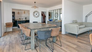 A modern kitchen with a large island, dining area with wicker chairs, and a sofa in a bright living space. - Villa 'Léa Vue Mer D'exception Plage' with Sea View, Private Terrace and Wi-Fi (Batz-sur-Mer)