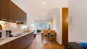 Una cocina moderna con armarios de madera, una zona de comedor con mesa y sillas, y vistas al exterior.