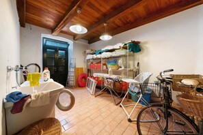 A laundry room with a washing machine, drying rack, bicycle, and shelves with various items. - Apartment 'Chéz Dede' with Balcony and Wi-Fi (Levanto)
