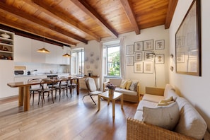 A spacious living area with a wooden dining table, chairs, a sofa, and a kitchen in the background. - Apartment 'Chéz Dede' with Balcony and Wi-Fi (Levanto)