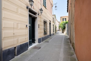 Una calle estrecha flanqueada por edificios, cielo despejado y una puerta visible a la izquierda.