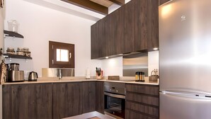 A modern kitchen with dark wood cabinets, stainless steel appliances, and a tiled floor. - Holiday Home 'Pescadores' with Sea View, Private Terrace and Air Conditioning (Son Moll)