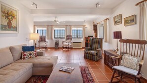 A spacious living room with a sofa, armchairs, a wooden rocking chair, a coffee table, and a fireplace. - Holiday Home 'Leo' with Sea View, Wi-Fi and Air Conditioning (Faro)