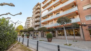 A multi-story residential building with balconies, a storefront with signage, and potted plants along the sidewalk. - Apartment 'Mestral' with Balcony, Wi-Fi and Air Conditioning (Cambrils)
