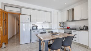 A modern kitchen with white cabinetry, a central island with chairs, and a dining area. - Apartment 'Mestral' with Balcony, Wi-Fi and Air Conditioning (Cambrils)