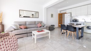 A modern living room with a sofa, a coffee table, and a dining area with chairs and a table. - Apartment 'Mestral' with Balcony, Wi-Fi and Air Conditioning (Cambrils)
