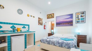 Una habitación con cama, escritorio, refrigerador y baño.