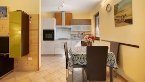 A modern kitchen with wooden cabinets, a dining table with chairs, and a clock on the wall. - Apartment 'Chateau Chatillon' with Mountain View, Private Terrace and Wi-Fi (Châtillon)