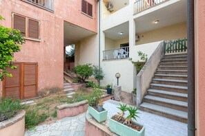 A multi-level residential building with a staircase, potted plants, and a small outdoor seating area.